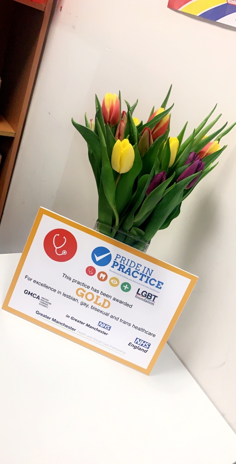 The certificate for the gold award in front of a vase of tulips